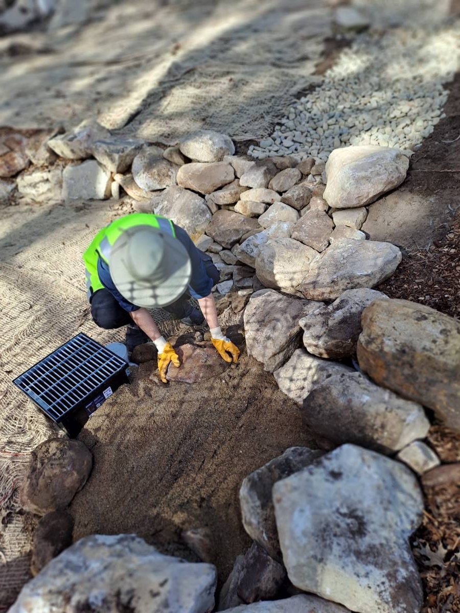 Amy gathers sandy soil around the stormwater drain in the newly created pond,